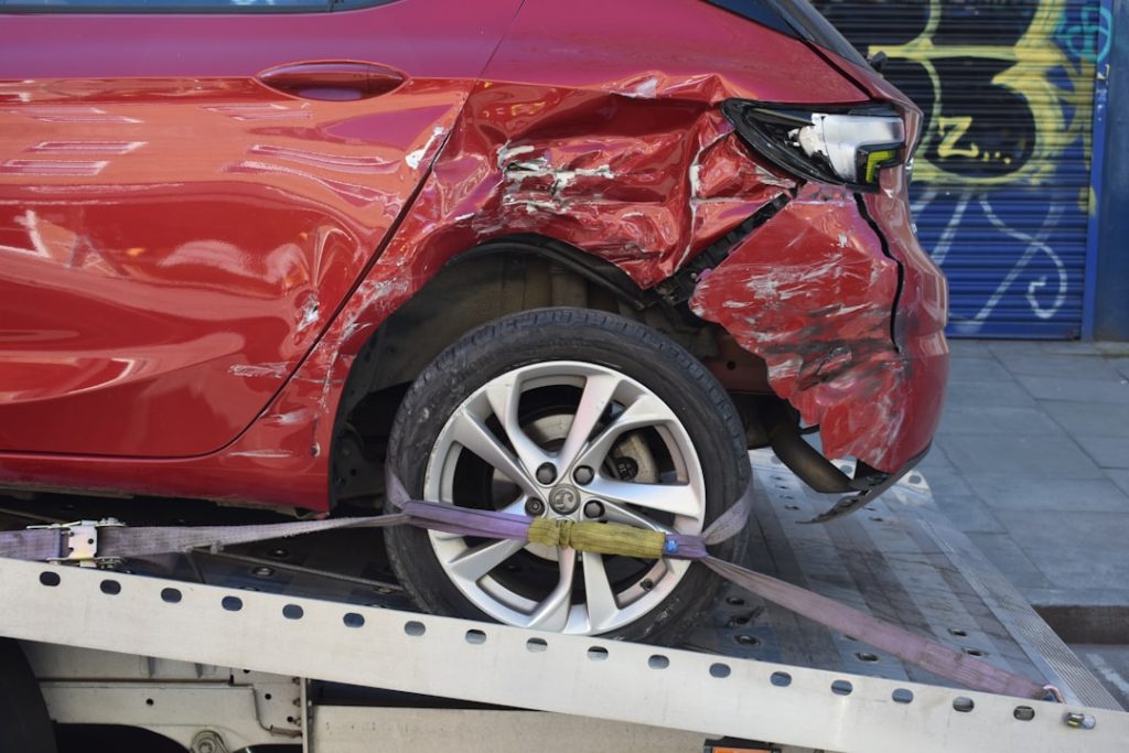 Image of a red car being towed/recovered which was involved in a road traffic collision.